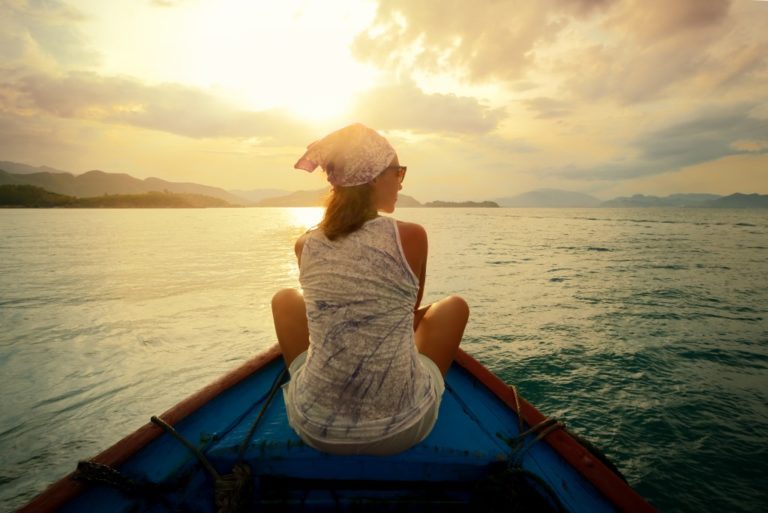 Girl sitting on a boat by the sunset